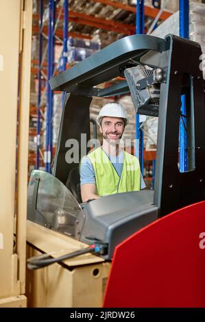 Lächelnder Lagerangestellter saß im Gabelstapler Stockfoto