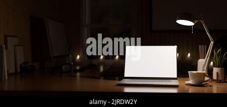 Moderner Vintage-Home-Arbeitsplatz bei Nacht mit Laptop weißen Bildschirm Modell unter dem schwachen Licht von Tischlampe, Zubehör und Kopierer Platz auf Holz Tisch o Stockfoto