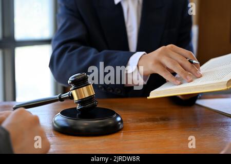 Nahaufnahme, Ein männlicher Anwalt oder Rechtsberater, der im Büro arbeitet oder Rechtsbuch liest, Beratung und Treffen mit seinem Mandanten. Stockfoto