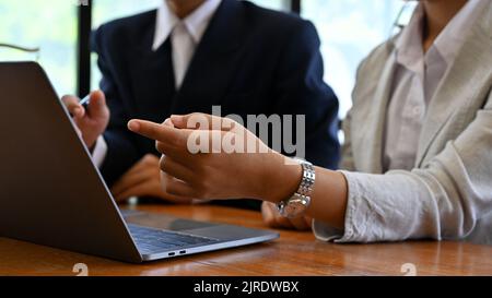 Eine professionelle und kompetente Finanzanalytikerin, die die Finanzdaten auf einem Tablet-Bildschirm betrachtet und mit ihrer Kollegin im Büro zusammenarbeitet. Cropped imag Stockfoto