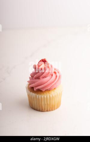 Eine vertikale Aufnahme eines Vanille-Cupcake mit Erdbeercreme isoliert auf weißem Hintergrund Stockfoto