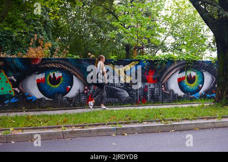 Krakau, Polen. 23. August 2022. Eine Frau kommt an einem neu bemalten Wandgemälde vorbei, das die polnische Solidarität mit der Ukraine während der russischen Invasion zeigt. Krakau, Polen, am 23. August 2022. Das Wandgemälde wurde vom polnischen Straßenkünstler Mikolaj Rejs mit Hilfe ukrainischer Kinder und des kalifornischen Künstlers Benjamin Ssatez von der gemeinnützigen Organisation Goodness Tour gemalt. (Bild: © Beata Zawrzel/ZUMA Press Wire) Stockfoto