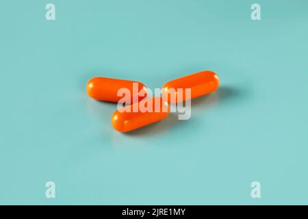 Drei Stücke Medizin in Form von orangen Kaplets Stockfoto