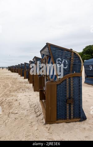 Reihen von blauen Rattanhütten am Strand an einem bewölkten Tag. Keine Touristen am Strand. Stockfoto