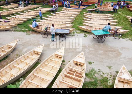 Manikganj, Dhaka, Bangladesch. 24. August 2022. Hunderte von handgefertigten Holzbooten stehen auf dem größten Bootsmarkt von Bangladesch in Manikgonj, Bangladesch, zum Verkauf. Wird von den Einheimischen während des Monsuns verwendet Wenn starke Niederschläge das Flussufer zum Platzen bringen, kostet jedes Schiff zwischen Â£30 und Â£80, abhängig von seiner Größe und der Qualität der verwendeten Materialien. Die Menschen strömten auf den Freiluftmarkt, um Boote zu kaufen, um sich auf die kommende Regenzeit vorzubereiten. Kredit: ZUMA Press, Inc./Alamy Live Nachrichten Stockfoto