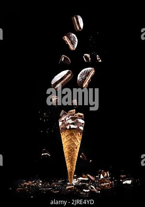 Cookies N' Cream Eis auf schwarzem Hintergrund in einem Waffelbecher. Eis mit Cookies Levitation Stockfoto