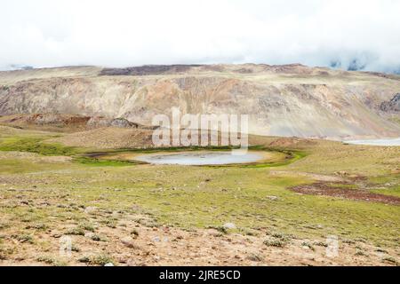 Einzelnes, abgelegenes Sinkhole am Upper Chandra Taal Lake im Spiti Valley mit Berglandschaft Stockfoto