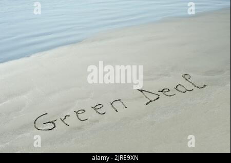 Konzept oder Konzept Green Deal handgeschriebener Text im Sand an einem Strand mit Wellen auf einer exotischen Insel für Sommer, Meer, Meer, Umwelt Stockfoto