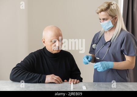 Coronavirus-Test - Medizinischer Mitarbeiter, der einen Tupfer für Coronavirus-Probe eines potenziell infizierten älteren Mannes mit chirurgischen Gesichtsmasken nimmt Stockfoto