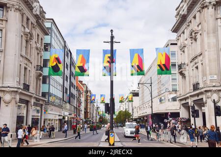 London, Großbritannien. 24.. August 2022. Entlang der Oxford Street wurde eine Kunstinstallation mit Fahnen mit der Aufschrift „Time for Clean Power“ aus recyceltem Ozeanplastik installiert, um den Wechsel zu erneuerbaren Energien zu fördern. Die Installation wurde vom britischen Künstler Morag Myerscough entworfen, der Teil einer von #TOGETHERBAND finanzierten Kampagne ist. Kredit: Vuk Valcic/Alamy Live Nachrichten Stockfoto