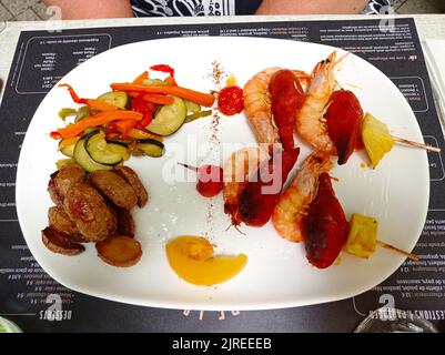 UN plat dans un Restaurant français, chorizo, crevettes, ananas, tomate cerise chauds, légumes, pommes de terre Stockfoto