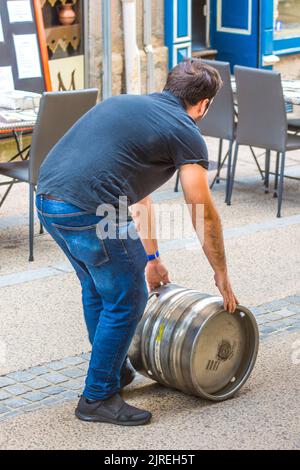 Der Lieferer rollt ein Metallfass Bier entlang der Straße - Limoges, Haute-Vienne (87), Frankreich. Stockfoto