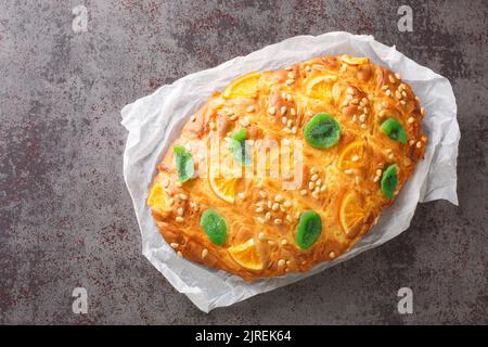 Coca de Sant Joan ist das süße Fladenbrot, gekrönt mit Pinienkernen oder kandierten Früchten in der Nähe auf dem Papier auf dem Tisch. Horizontale Draufsicht von oben Stockfoto