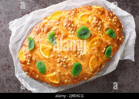 Traditionelle spanische katalanische Coca de Sant Joan mit Pinienkernen, kandierte Früchte aus der Nähe auf dem Papier auf dem Tisch. Horizontale Draufsicht von oben Stockfoto