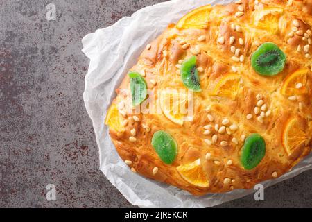 Spanisches festliches Brot Coca de sant joan mit Pinienkernen, kandierte Früchte Nahaufnahme auf dem Papier auf dem Tisch. Horizontale Draufsicht von oben Stockfoto