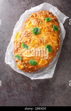 St Johns Kuchen Coca de sant joan mit Pinienkernen, kandierte Früchte Nahaufnahme auf dem Papier auf dem Tisch. Vertikale Draufsicht von oben Stockfoto