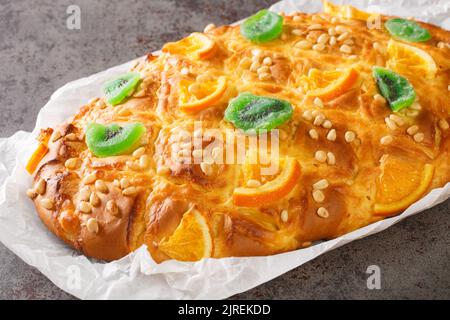 Traditionelle spanische katalanische Coca de Sant Joan mit Pinienkernen, kandierte Früchte aus der Nähe auf dem Papier auf dem Tisch. Horizontal Stockfoto