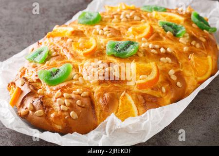 Spanisches festliches Brot Coca de sant joan mit Pinienkernen, kandierte Früchte Nahaufnahme auf dem Papier auf dem Tisch. Horizontal Stockfoto