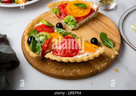 Nahaufnahme von geschnittenen Quiche mit Käse und Tomaten auf dem Küchenbrett Stockfoto
