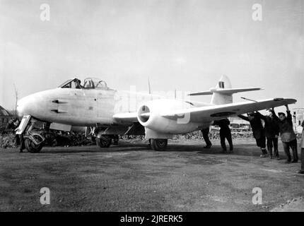 Die Bodenbesatzung manage am 6. Februar 1945 eine Gloster Meteor F.3 der 616 Squadron-Abteilung bei B58/Melsbroek, Belgien. Das Flugzeug war auf dem Kontinent eingesetzt worden, um der Bedrohung durch den deutschen Düsenjäger aus dem Jahr Me262 entgegenzuwirken, der mit der Luftwaffe in Dienst gestellt worden war. Die Meteor war der erste britische Düsenjäger und das einzige Düsenflugzeug der Alliierten, das während des Zweiten Weltkriegs Kampfhandlungen erbrachte. Die Meteor flog erstmals 1943 und nahm am 27. Juli 1944 mit der RAF-Staffel Nr. 616 ihren Betrieb auf. Einige dieser Bilder wurden ausgewichen und verbrannt und wurden retuschiert, um sie zu entfernen Stockfoto