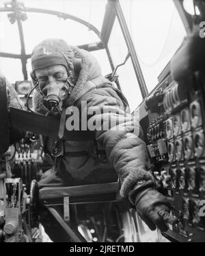 Royal Air Force Bomber Command, 1942-1945. Flying Officer J B Burnside, die als Flugingenieur an Bord eines Avro Lancaster B Mark III der Nr. 619 Squadron RAF in Coningsby, Lincolnshire, überprüft die Einstellungen auf dem Bedienfeld von seinem Sitz im Cockpit. Stockfoto