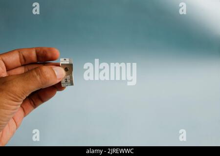 Nahaufnahme der Hand, die das Messband isoliert auf blauem Hintergrund hält Stockfoto