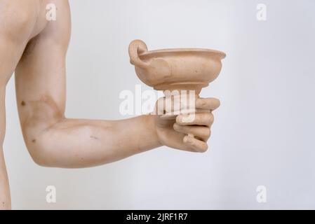 Nahaufnahme einer antiken Marmorstatue mit einer Tasse Stockfoto