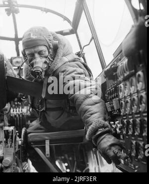 Royal Air Force Bomber Command, 1942-1945. Flying Officer J B Burnside, die als Flugingenieur an Bord eines Avro Lancaster B Mark III der Nr. 619 Squadron RAF in Coningsby, Lincolnshire, überprüft die Einstellungen auf dem Bedienfeld von seinem Sitz im Cockpit. Stockfoto