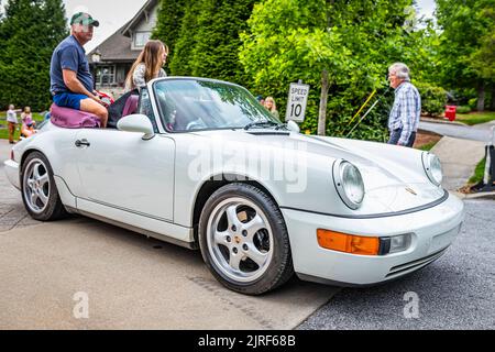 Highlands, NC - 10. Juni 2022: Vorderansicht eines Porsche 911 Carrera 4 Cabriolets aus dem Jahr 1991, das auf einer Straße fährt, die eine lokale Autoliste verlässt Stockfoto