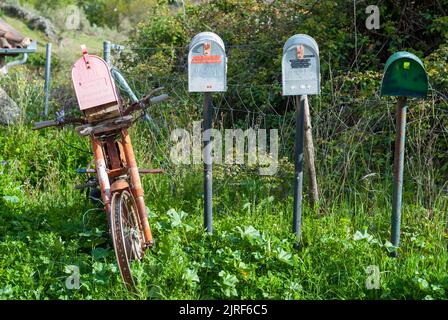 Recycelte Retro-Briefkästen mit alten rostigen Vintage-Motorrad auf dem Land Stockfoto