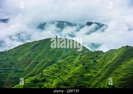 Hügel im Himalaya mit grünen Bäumen, die von Nebel bedeckt sind, und weißen Wolken nach einem Regen. Uttarakhand Indien. Stockfoto