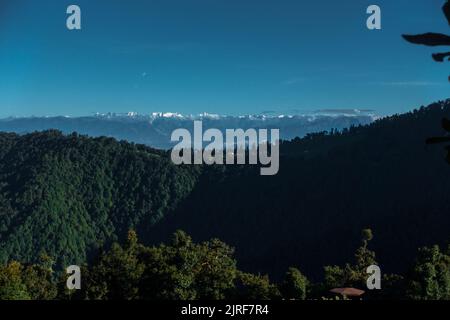 Ein entfernter Panoramablick auf schneebedeckte Berggipfel des Gomukh-Gletschers mit Waldbedeckung im oberen Himalaya. Uttarakhand Indien. Stockfoto