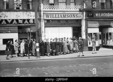 Hausfrauen Warteschlange außerhalb der Bäcker und Konditor" Williamson's" auf High Road, Wood Green, London 1945. Hausfrauen Warteschlange außerhalb der Bäcker und Konditor" Williamson's" auf der Hohe Straße, Holz Grün. Die Legende besagt, dass "es gibt viel Brot in den Shop, aber die Hausfrauen sind Queuing für Kuchen. Sie müssen etwas für Kaffee, wenn der alte Mann von der Arbeit nach Hause kommt und die Kuchen werden direkt riß sie im Fenster gesetzt werden". Stockfoto