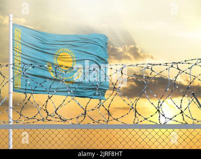 Fahnenmast mit der Flagge Kasachstans gegen den Himmel und hinter einem Zaun mit Stacheldraht. Das Konzept des Schutzes der Grenzen von Gebieten. Stockfoto