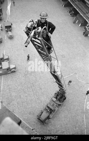 Die Mitglieder der Feuerwehr Ausbildung bei der Londoner Feuerwehr Hauptquartier 1940. Ein Mitglied der Feuerwehr steht an der Spitze einer teilweise ausgefahren Drehleiter während einer Übung an der Londoner Feuerwehr Hauptquartier. Stockfoto