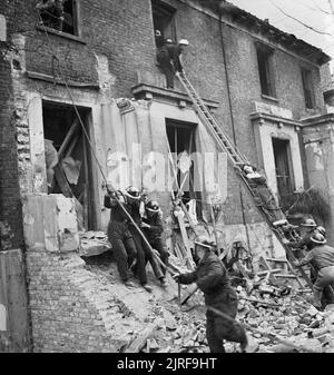 Mitglieder einer schweren Rettungspartei evakuieren Zivilisten aus einem bombenbeschädigten Gebäude während einer groß angelegten Zivilverteidigungsübung im Jahr 1942 in Fulham. Stockfoto