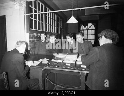 16-jährigen Registrieren - Jugendliche ihre Erwachsenen ID-Karten von der Labour Exchange, London, England, UK, 1945 eine Gruppe von 16-jährigen Jungen im Arbeitsamt, Islington kommen für ihre erwachsenen Identität Karten zu registrieren. Von links nach rechts sind es: Roy Clements (Verfasser der Stellungnahme), Robert Hinch (rollgeld Auftragnehmer workman), James Beck (Untersuchung eines kommerziellen Künstler zu sein) und James Pickering (junior Sekretärin). Pickering hat sich freiwillig für die Handelsmarine, und ist an der Börse nicht für seine ID-Karte zu registrieren, aber die endgültige Genehmigung seiner jetzigen Job zu verlassen, zu erhalten. Gemäß der ursprünglichen Stockfoto