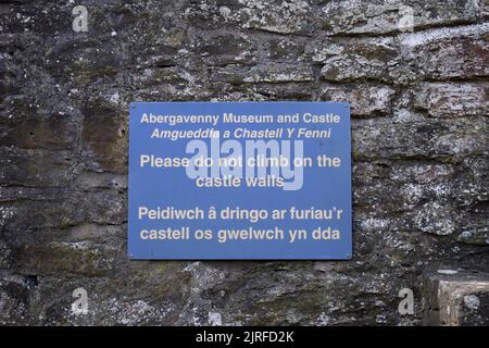 Melden Sie sich auf Englisch und Walisisch an und warnen Sie die Menschen, nicht auf die Burgmauern zu klettern, Abergavenny Castle, Wales, Inited Kingdom Stockfoto