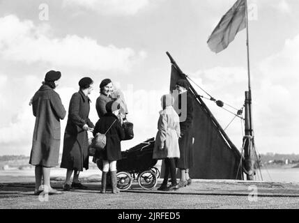 Eine Gruppe von evakuiert Mütter und Kinder aus London um Bideford Hafen in North Devon während 1941. Eine Gruppe von evakuiert Mütter und Kinder miteinander plaudern am Kai in Bideford Hafen in North Devon im Jahre 1941. Sie sind Frau Bresnet von Camberwell, Frau Stand von Sydenham, Frau Bailey und ihre zwei Jahre alte Tochter Jane von Catford und Frau Hewson und ihre Kinder Ronald (im Alter von 3) und Denise (7 Jahre alt) aus Croydon. Gerade hinter Ihnen, das Segel von einem kleinen Boot gesehen werden kann. Stockfoto