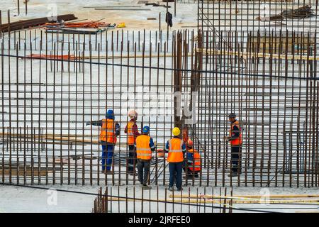 RUSSLAND, KALUGA - 15. AUGUST 2022 : Eine Gruppe von Arbeitern, die den Rahmen eines Gebäudes aus Eisenbeschlägen zusammenbauen. Stockfoto