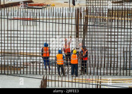 RUSSLAND, KALUGA - 15. AUGUST 2022 : Eine Gruppe von Arbeitern, die den Rahmen eines Gebäudes aus Eisenbeschlägen zusammenbauen. Stockfoto