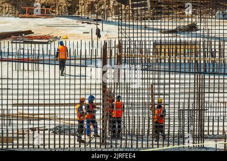 RUSSLAND, KALUGA - 15. AUGUST 2022 : Eine Gruppe von Arbeitern, die den Rahmen eines Gebäudes aus Eisenbeschlägen zusammenbauen. Stockfoto