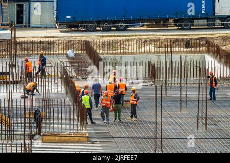 RUSSLAND, KALUGA - 15. AUGUST 2022 : Eine Gruppe von Arbeitern, die den Rahmen eines Gebäudes aus Eisenbeschlägen zusammenbauen. Stockfoto