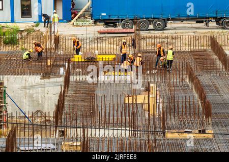 RUSSLAND, KALUGA - 15. AUGUST 2022 : Eine Gruppe von Arbeitern, die den Rahmen eines Gebäudes aus Eisenbeschlägen zusammenbauen. Stockfoto