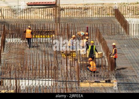 RUSSLAND, KALUGA - 15. AUGUST 2022 : Eine Gruppe von Arbeitern, die den Rahmen eines Gebäudes aus Eisenbeschlägen zusammenbauen. Stockfoto