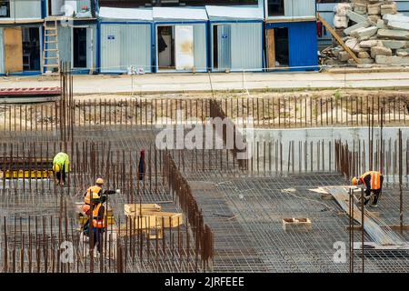 RUSSLAND, KALUGA - 15. AUGUST 2022 : Eine Gruppe von Arbeitern, die den Rahmen eines Gebäudes aus Eisenbeschlägen zusammenbauen. Stockfoto