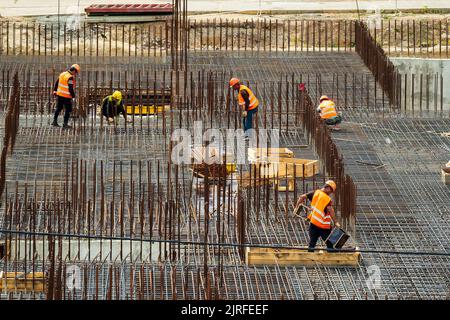 RUSSLAND, KALUGA - 15. AUGUST 2022 : Eine Gruppe von Arbeitern, die den Rahmen eines Gebäudes aus Eisenbeschlägen zusammenbauen. Stockfoto