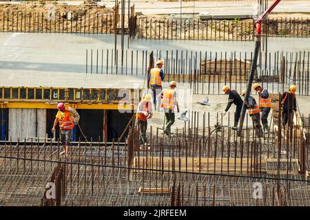 RUSSLAND, KALUGA - 15. AUGUST 2022 : Betonautomatisches Pumpenrohr, das auf der Baustelle arbeitet. Gruppe von Arbeitern, die Beton leiten und gießen. Stockfoto