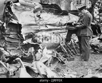 Luftwaffe Razzien in Großbritannien zwei ältere RAF Offiziere Untersuchung der Trümmer einer Heinkel He 111, die in Clacton, 1. Mai 1940 abgestürzt. Defensive der Bomber 7,92 mm MG 17 Maschinenpistolen und Munition Drums haben zusammen gesammelt worden. Stockfoto