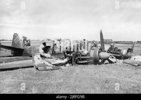 Die Schlacht um England RAF Personal Inspektion der ausgebrannten Wrack eines Junkers Ju 88 Aufklärungsflugzeug der 4.(F)/122 auf cockett Wick Farm, St. Osyth in der Nähe von Clacton-on-Sea, Essex. Das Flugzeug wurde abgeschossen, am 20. Juli 1940 durch Nr. 56 Squadron Hurrikane. Stockfoto